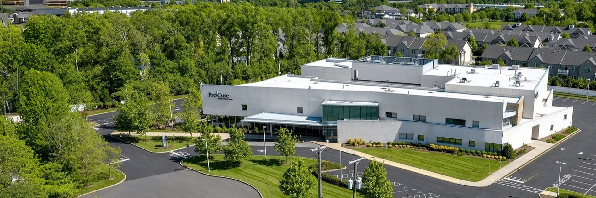 an outdoor aerial view of procure proton therapy center in somerset nj surrounded by trees and greenery